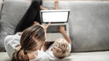 Mother sitting with child learning at home on the computer.