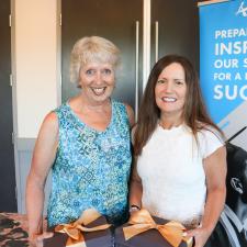 Two women pose for picture holding their retirement gifts